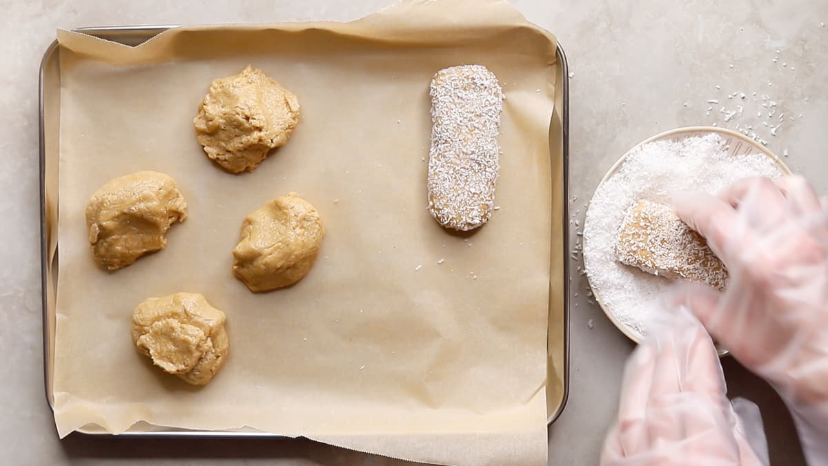 Protein bars being shaped and coated in desiccated coconut