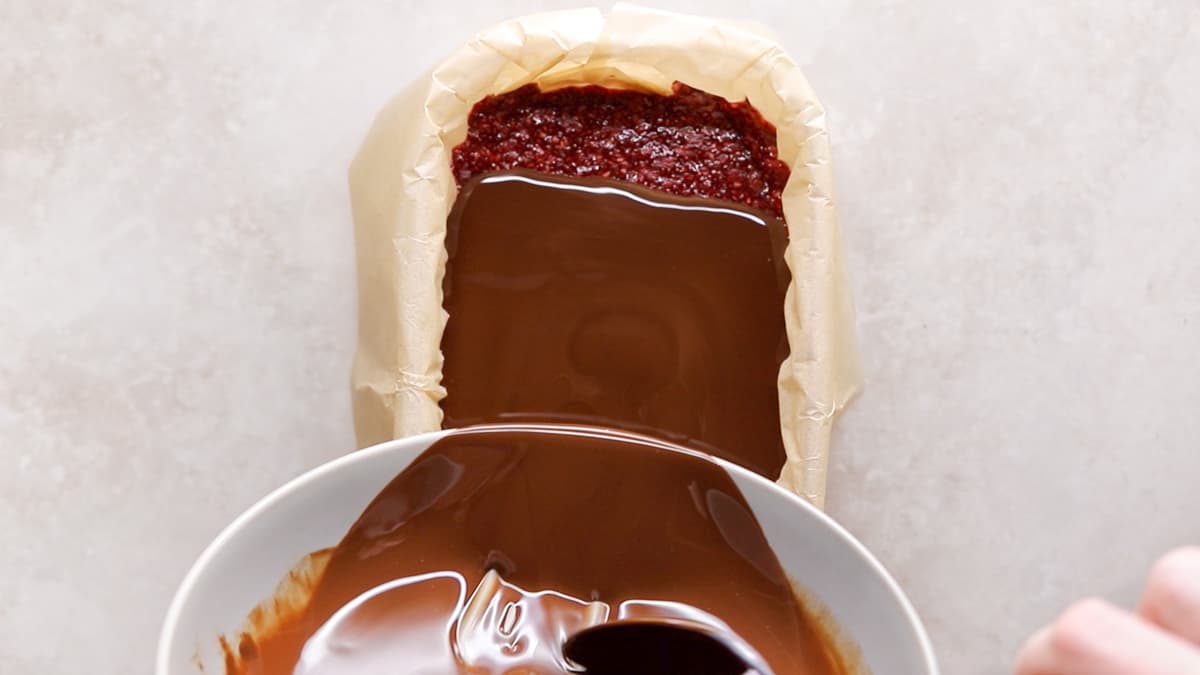 Melted chocolate being poured over slice