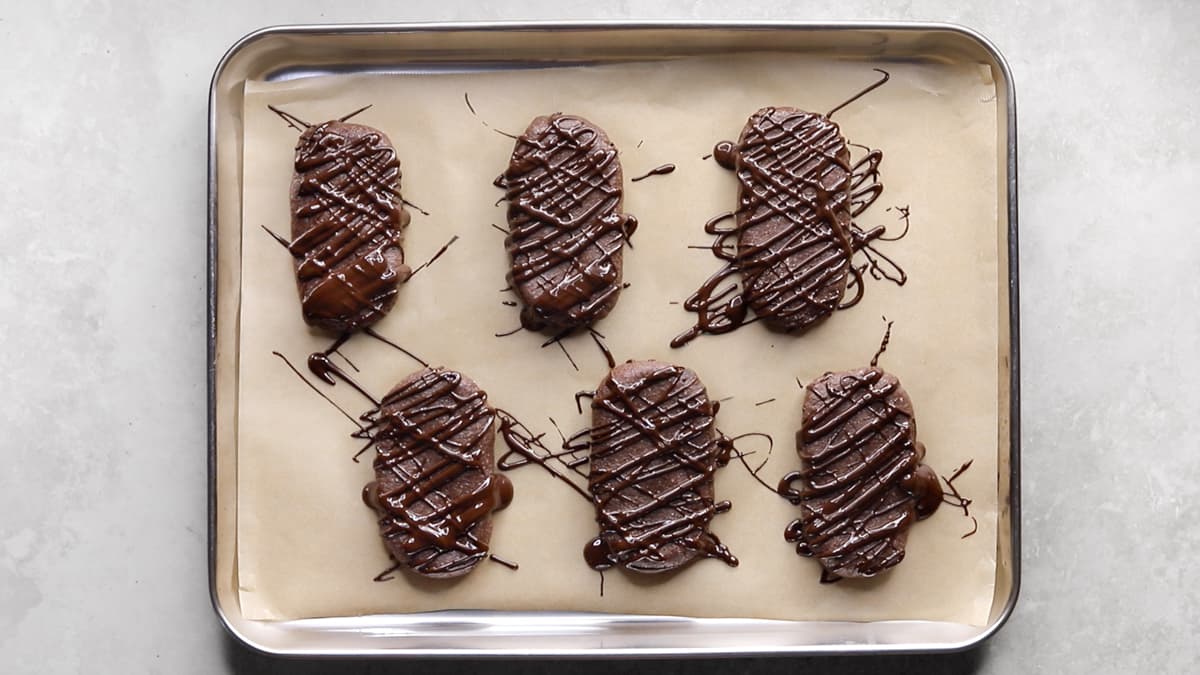 Protein bars drizzled with melted chocolate on a parchment-lined tray