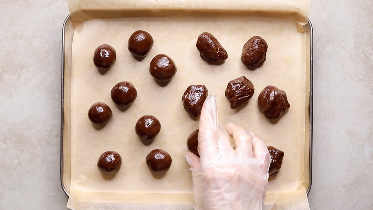 Choc mint protein dough being shaped into balls on a tray with baking paper