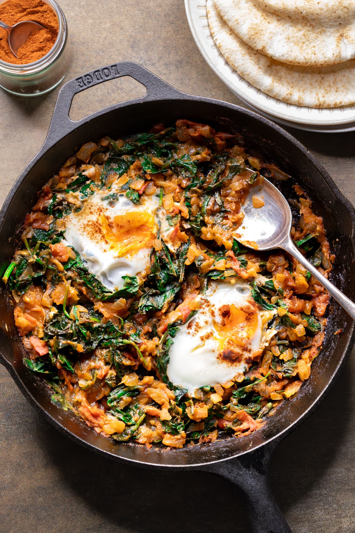 Shakshuka with fresh tomato, spinach and eggs sprinkled with smoked paprika