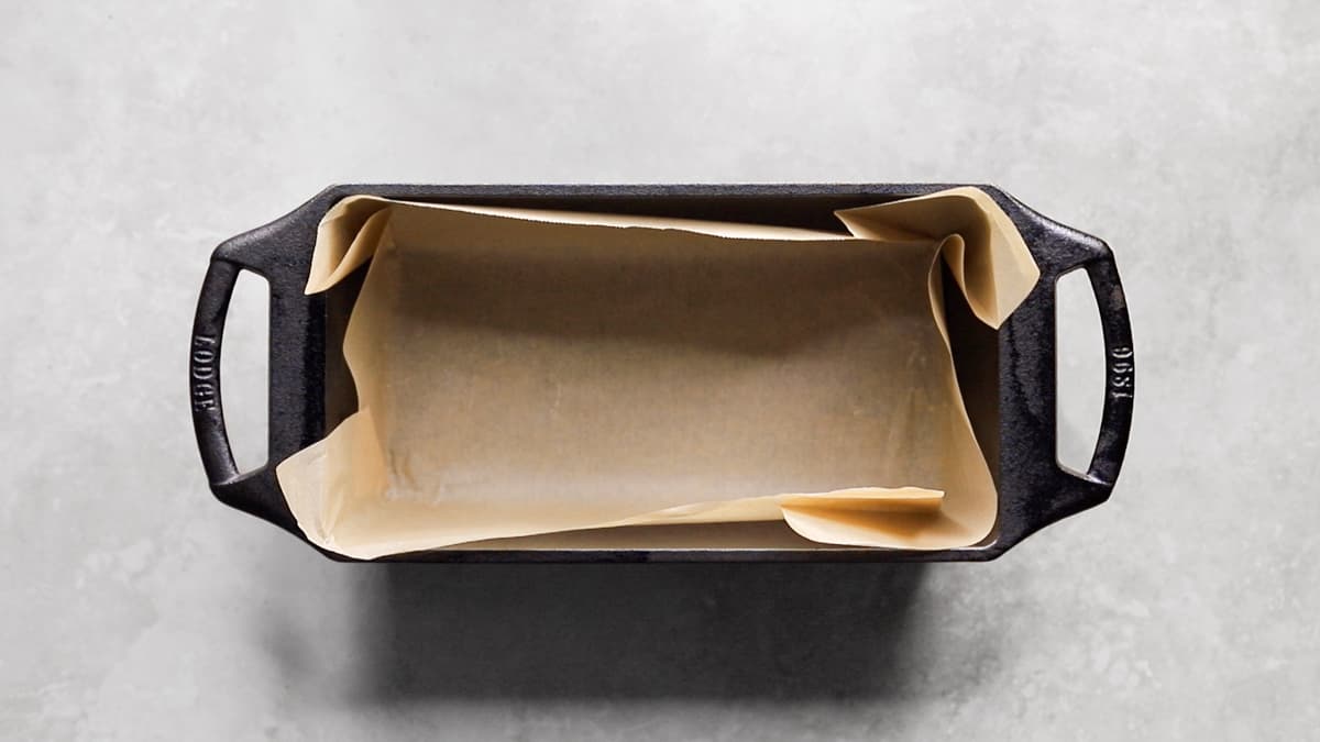 Cast iron loaf pan lined with parchment paper, ready for protein bar mixture