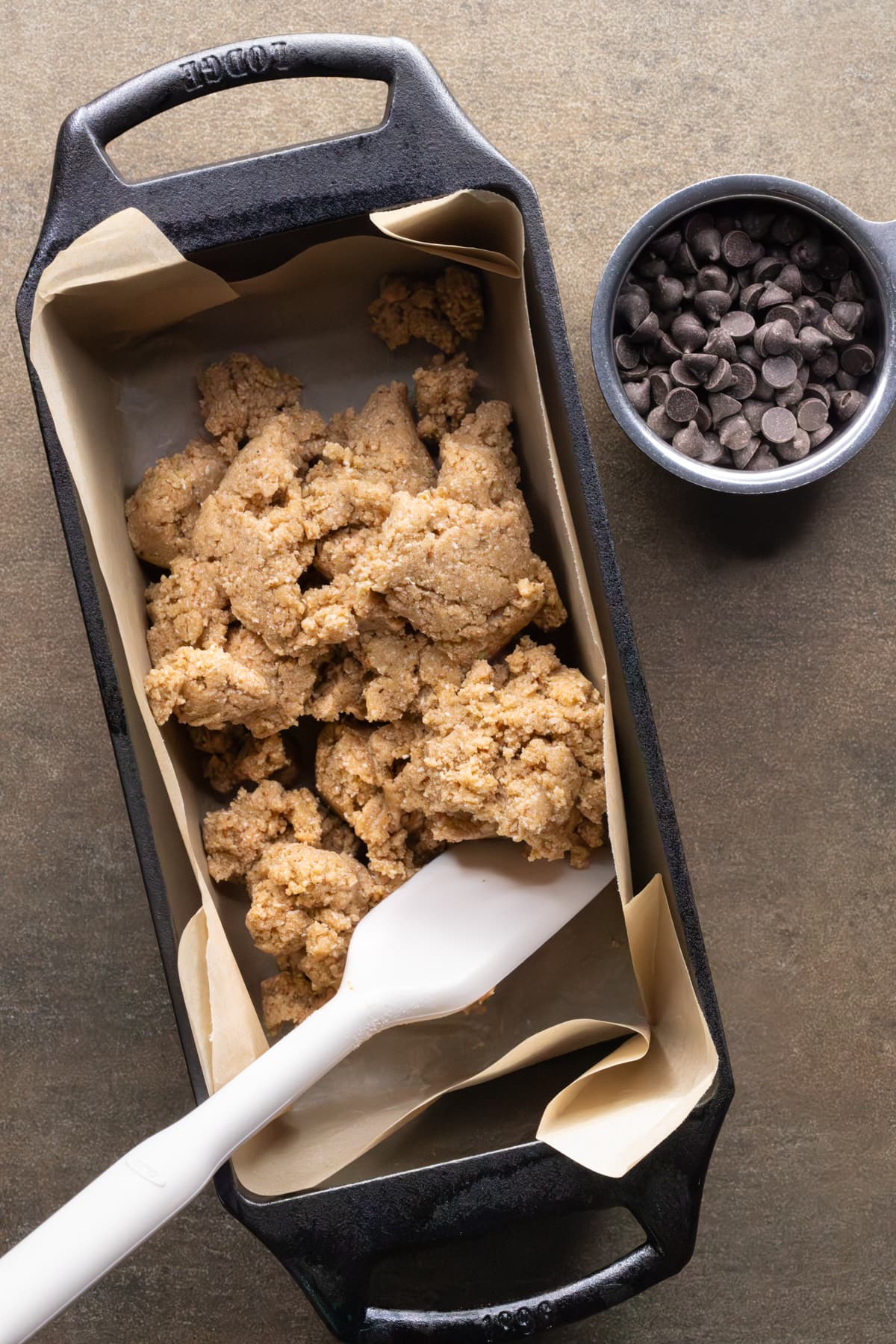 Protein bar dough in a loaf pan with a spatula