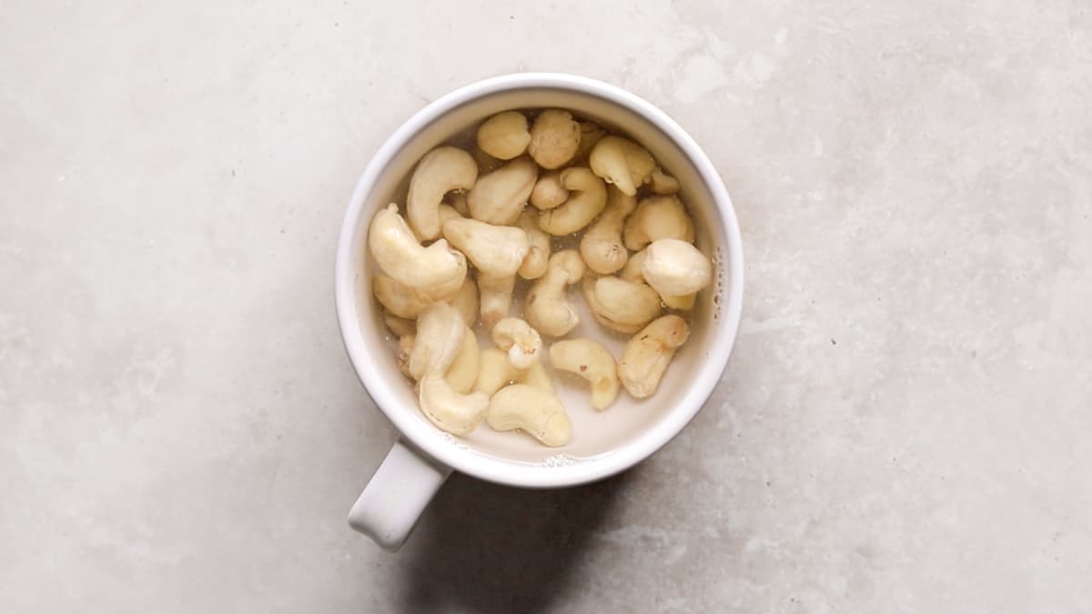 A cup of cashew nuts soaking in hot water