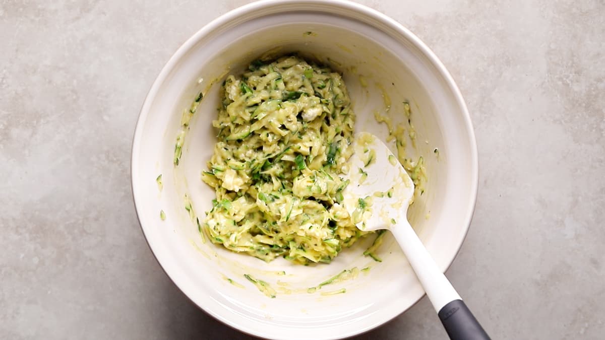 A mixing bowl filled with thick zucchini and feta fritter batter