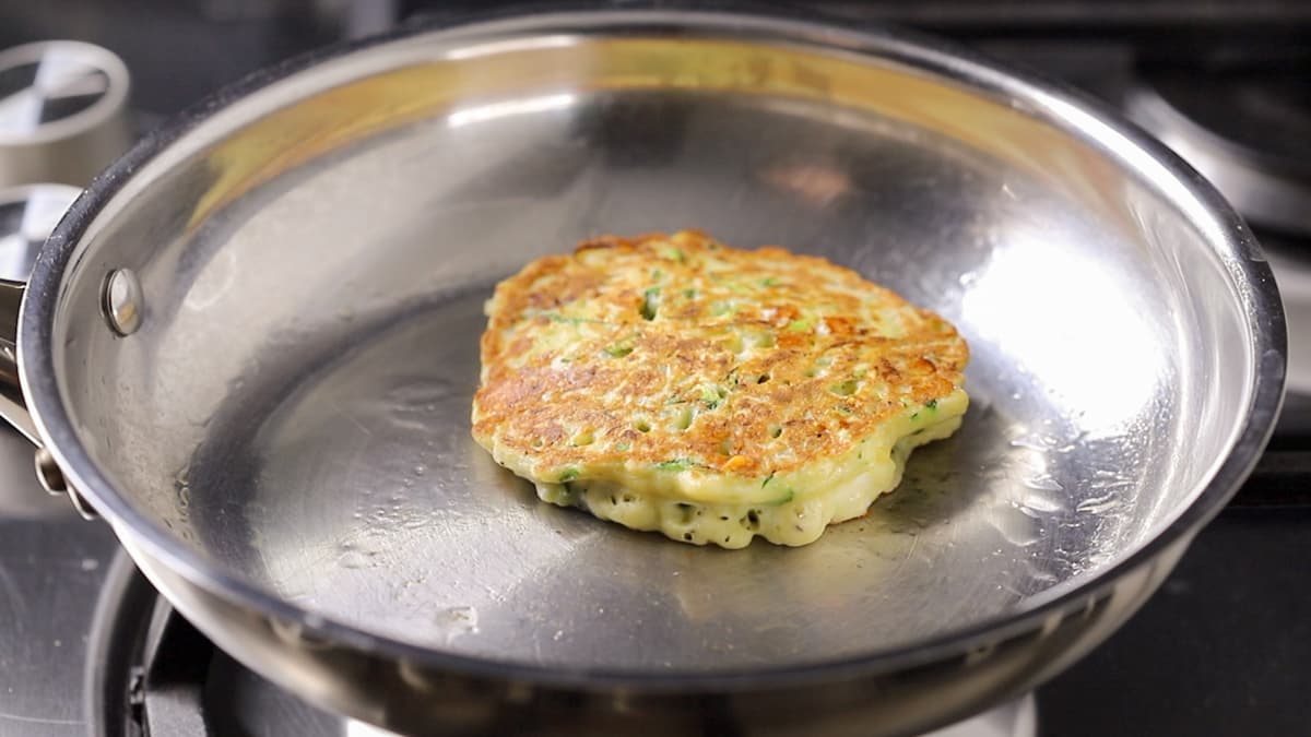 Zucchini and feta fritters frying in a pan