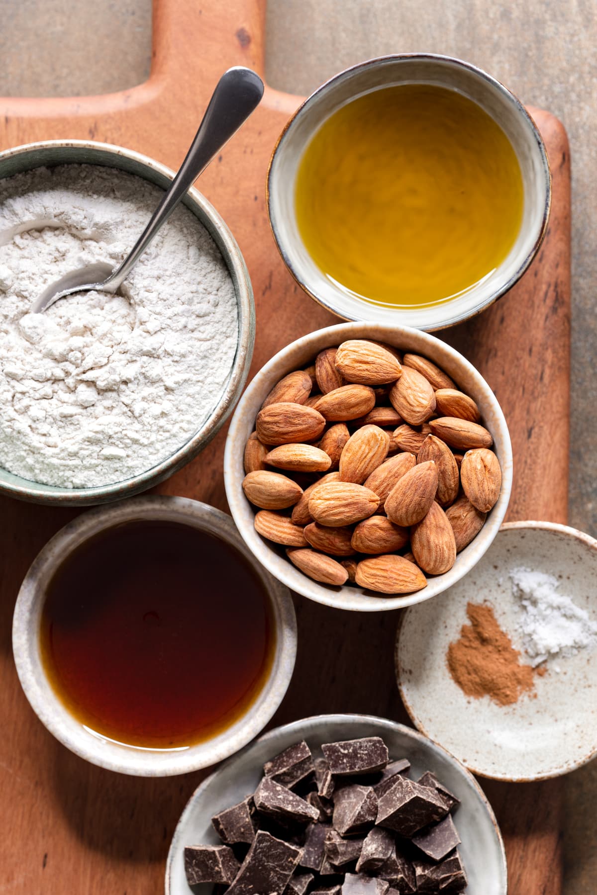 Ingredients for almond olive oil shortbread cookies in bowls on a wooden board