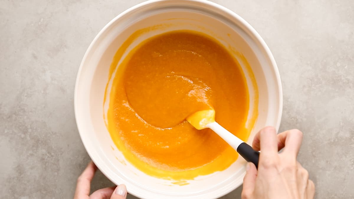 Bowl of pumpkin bread batter being mixed, showing smooth, orange gluten-free mixture