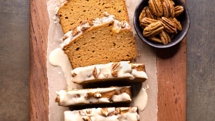 Easy gluten-free pumpkin bread on a wooden board with maple glaze and pecan nuts