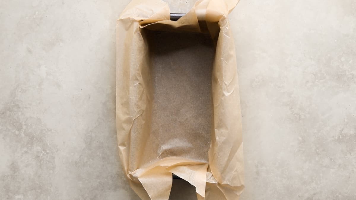 Loaf pan lined with baking paper, ready for pumpkin bread batter