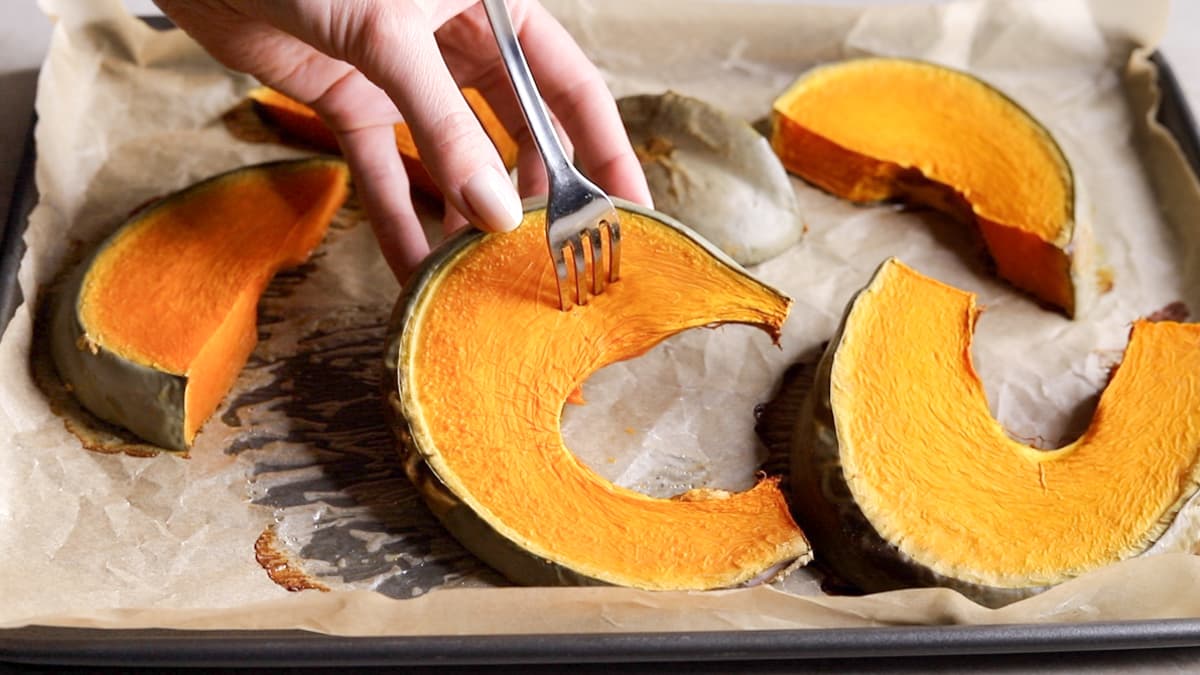 Baked pumpkin slice being tested with a fork