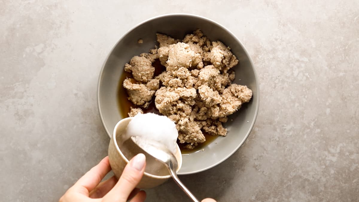 Adding coconut oil to cheesecake biscuit base in bowl