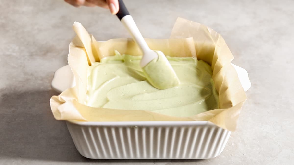 Spreading lime cheesecake filling into lined dish with spatula