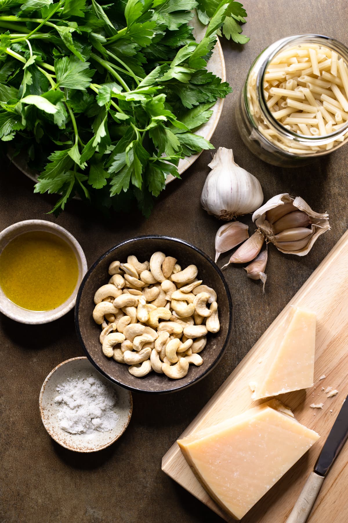 Ingredients for parsley pesto pasta with cashews set out in bowls