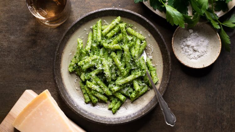 Parsley pesto pasta with cashew nuts served with Parmesan cheese