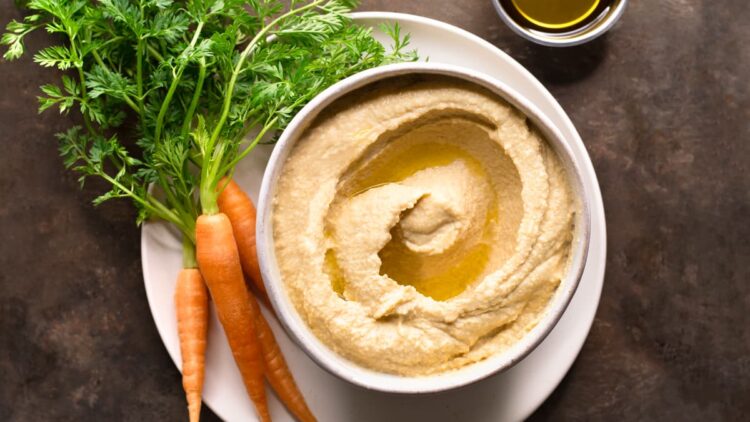 Hummus without lemon and garlic in a bowl with a bunch of baby carrots