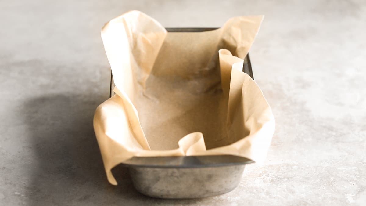 Loaf pan lined with baking paper ready for the cookie dough mixture