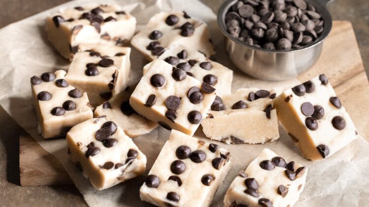 Protein bars with chocolate chips arranged on a wooden board covered with a sheet of baking paper