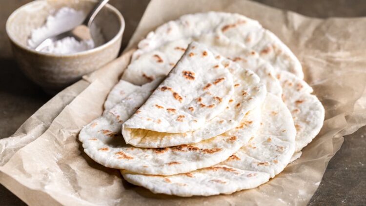 Gluten-free flatbread made with no yeast piled up on sheets of baking paper