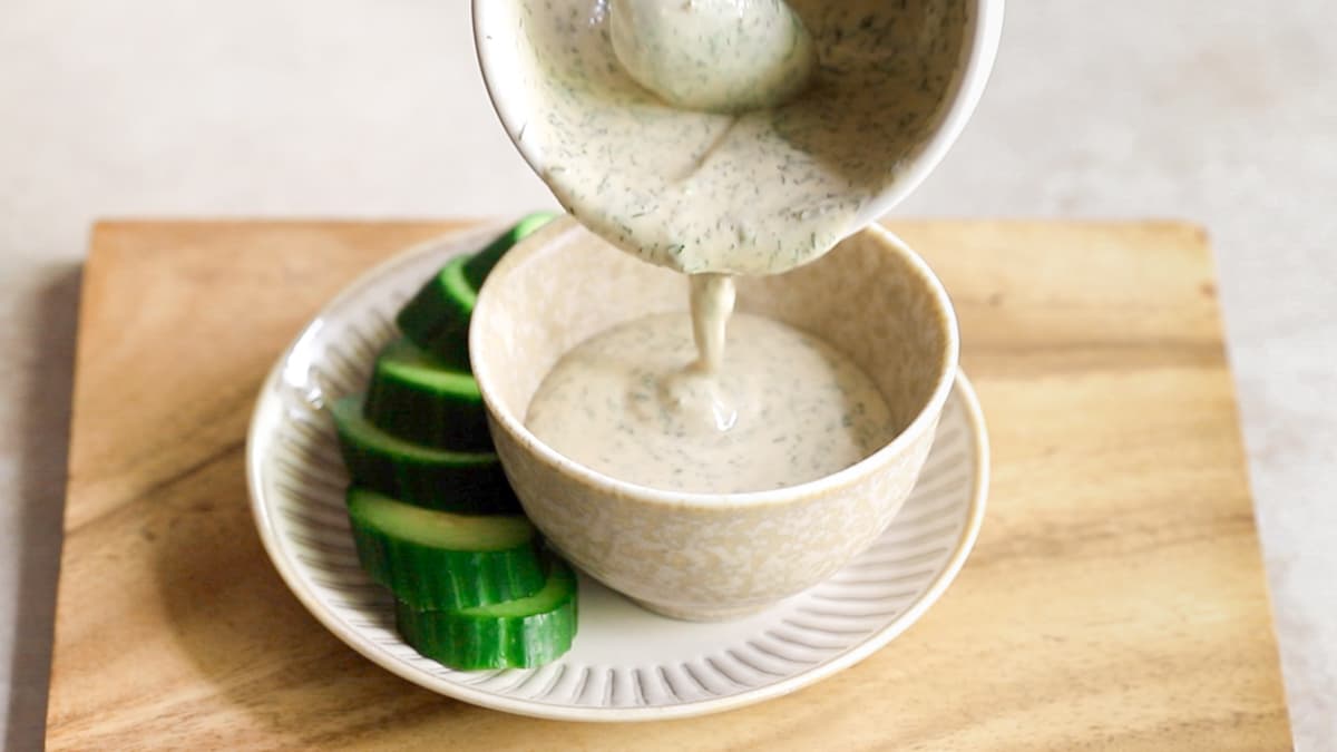 Creamy vegan tahini ranch dressing served with fresh cucumber slices