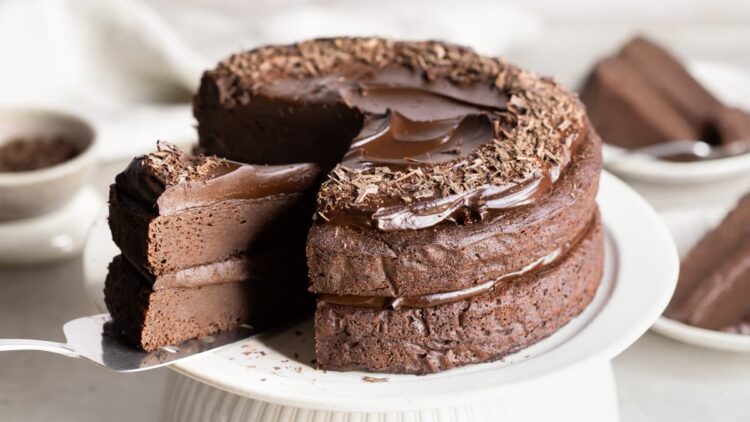 Vegan sweet potato chocolate fudge cake with a slice being removed with a cake server