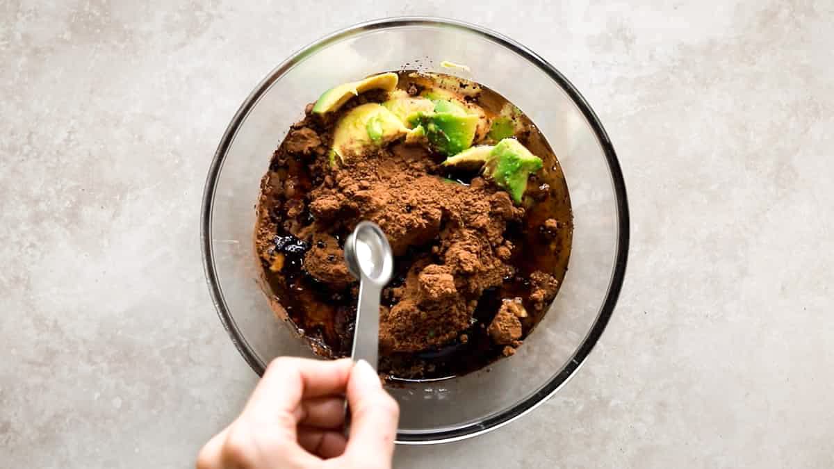Adding salt to bowl with avocado, cocoa powder, and maple syrup
