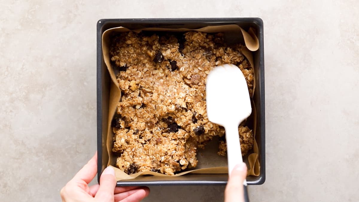 Oatmeal breakfast bar dough pressed into a lined baking pan
