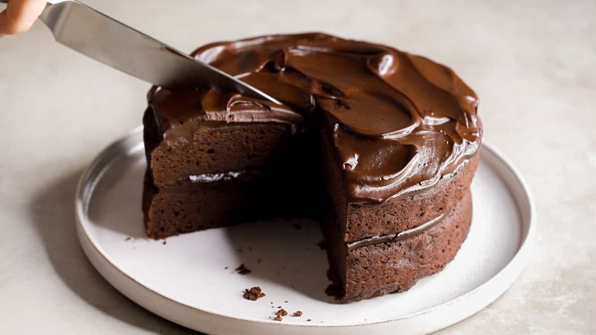 Cutting vegan avocado chocolate cake with knife