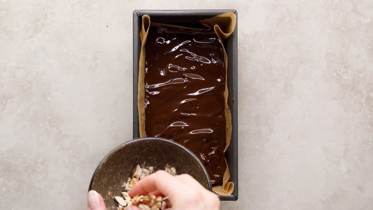 Top the no-bake protein bars with melted chocolate and crushed almonds