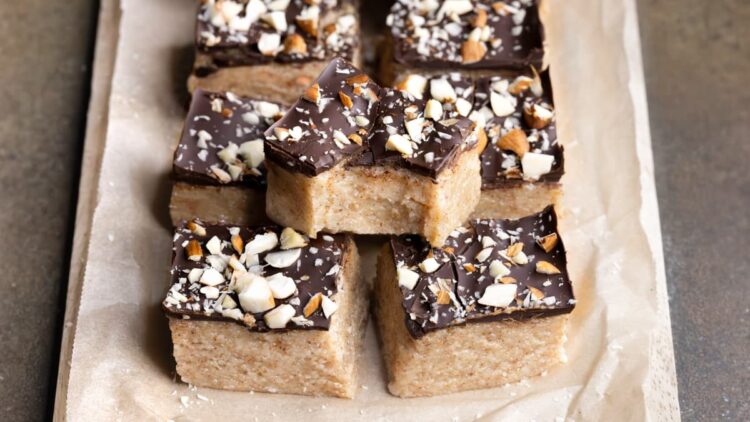 No-bake almond nougat protein bars decorated with dark chocolate and crush nuts