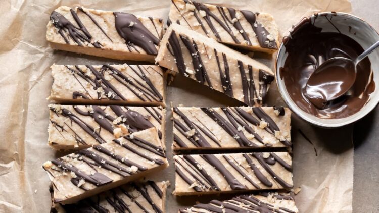 Vegan peanut butter oat protein bars with a drizzle of chocolate on a sheet of baking paper