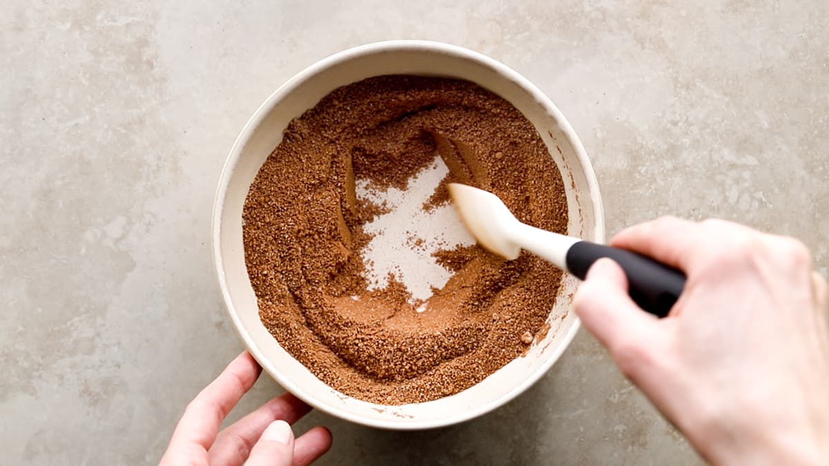 Mixing almond flour and cacao powder in bowl with spatula
