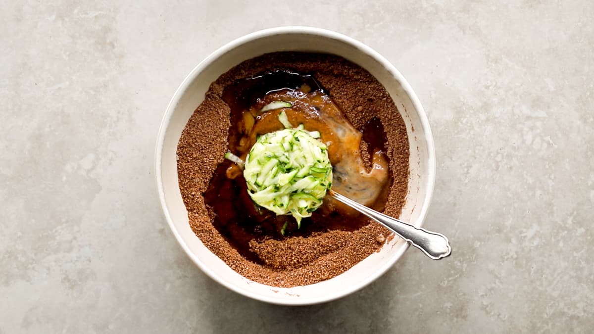 Mixing chocolate zucchini muffin batter with spoon in bowl