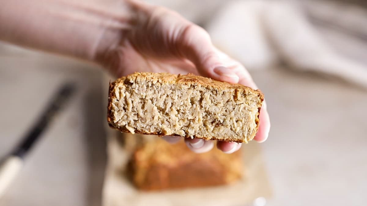 Banana cinnamon baked oatmeal protein bar held in hand, showing its texture and size