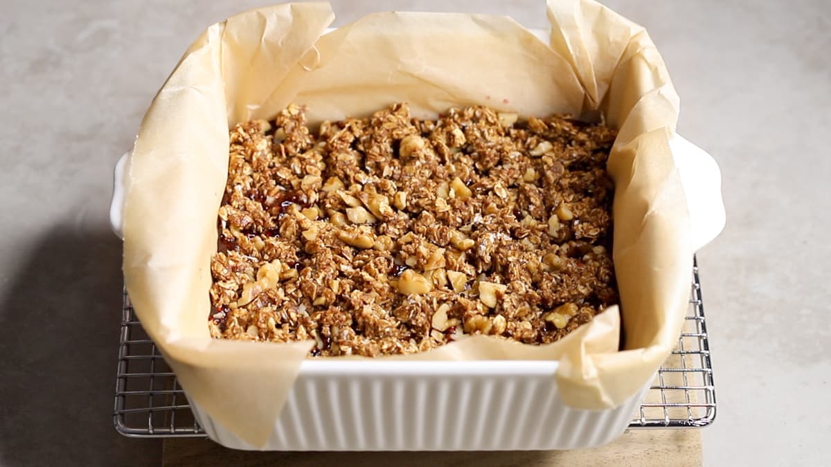 Top the oatmeal bar base with jam and the crumble mixture