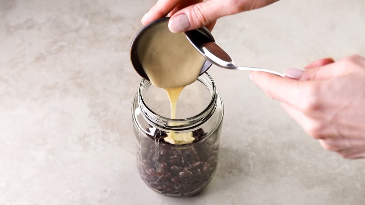 Glass jar filled with black beans and tahini