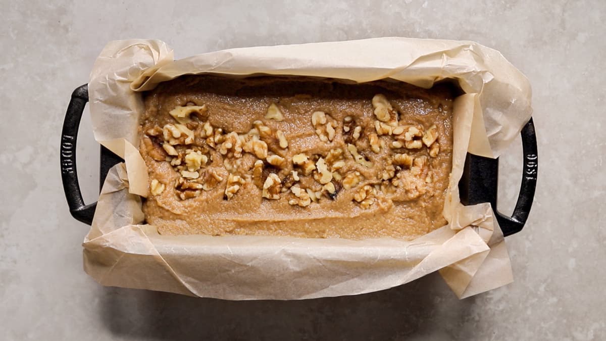 Coconut flour banana bread batter poured into a lined loaf pan, ready for baking