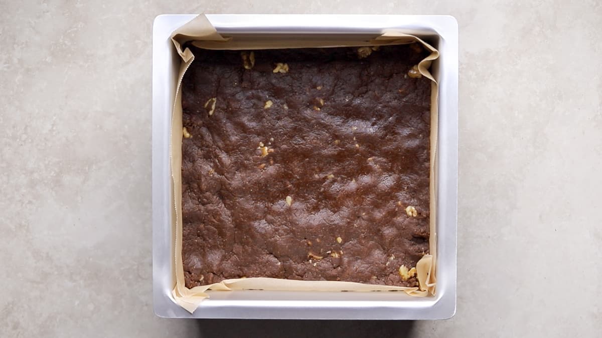 Press the brownie batter dough into a lined cake pan