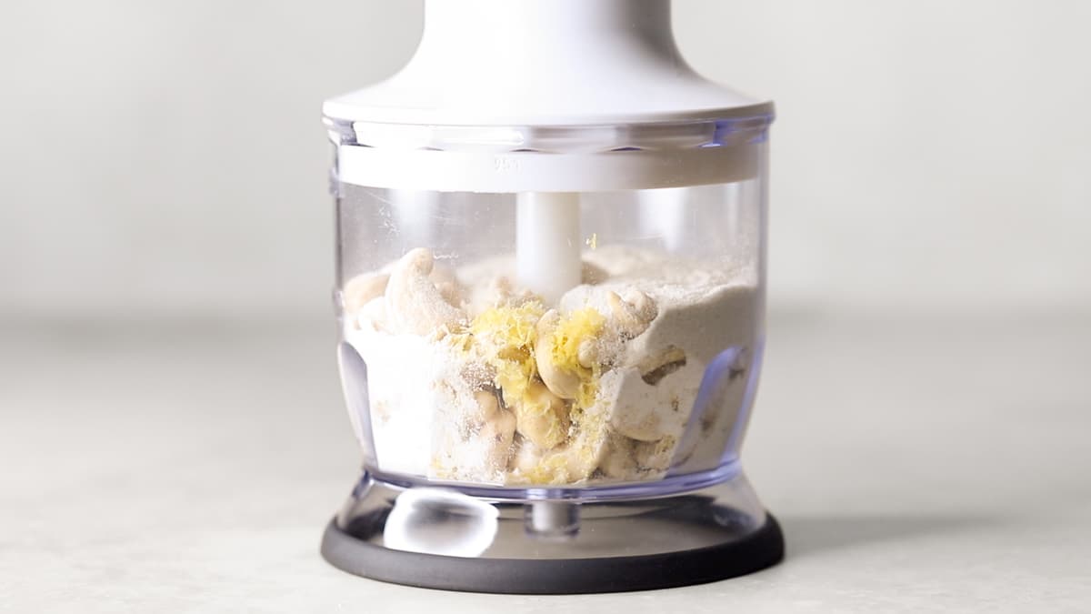 Cashews, lemon zest, and flour in a food processor bowl before blending