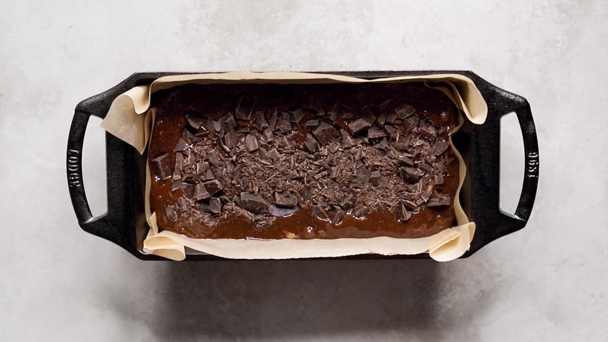 Pour the zucchini bread batter into the loaf pan and top with the remaining chopped chocolate