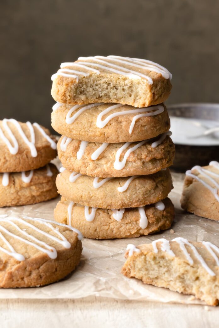 A stack of gluten-free lemon shortbread cookies, topped with a lemon icing drizzle