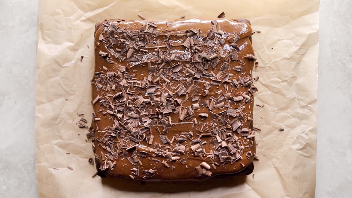 Spread the frosting over the chickpea chocolate cake and decorate with shaved chocolate
