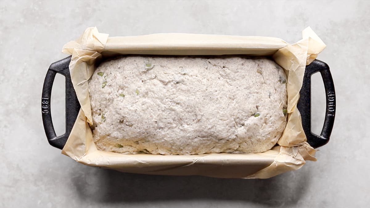 Unbaked bread dough in a parchment-lined loaf pan