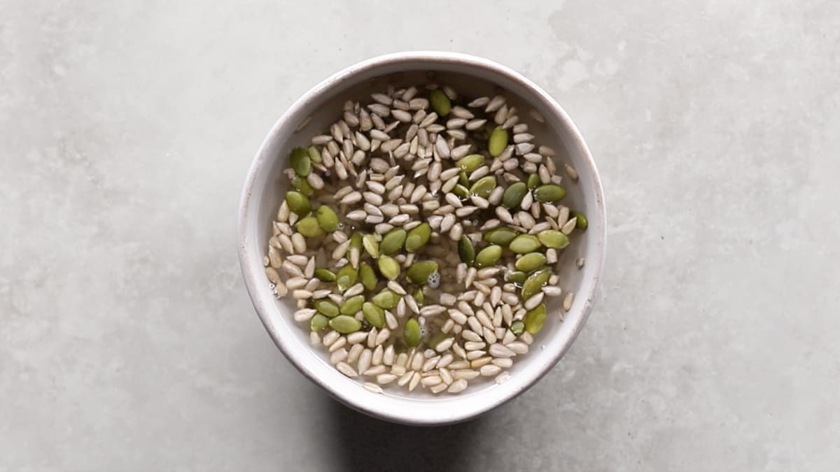 Pepitas and sunflower seeds soaking in water in a bowl
