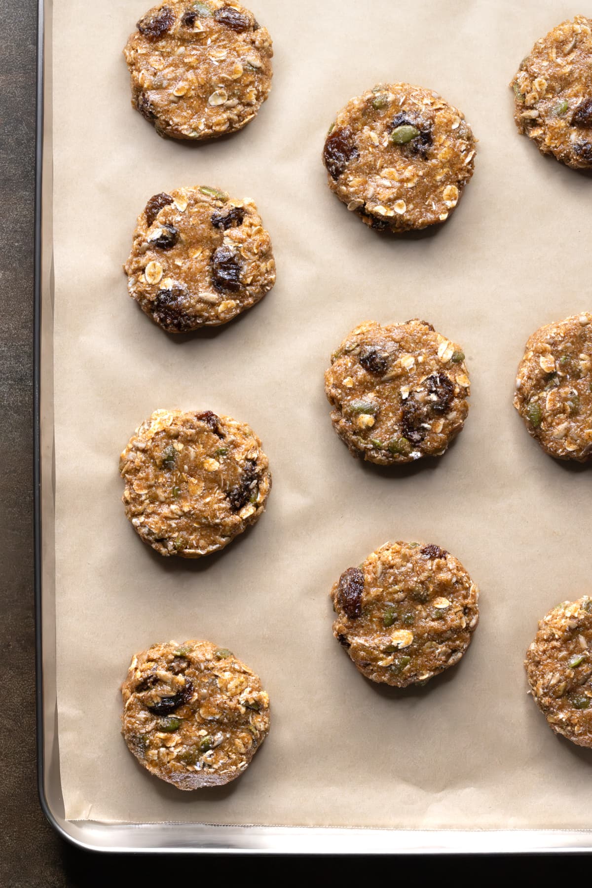 Shaped dough for oatmeal raisin cookies arranged on a baking sheet ready to bake