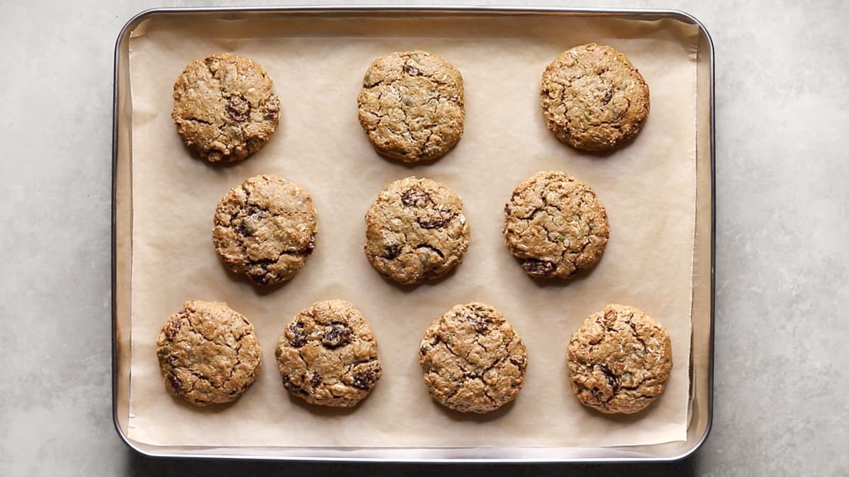 Freshly baked oatmeal raisin cookies on a tray with a golden-brown color and visible raisins