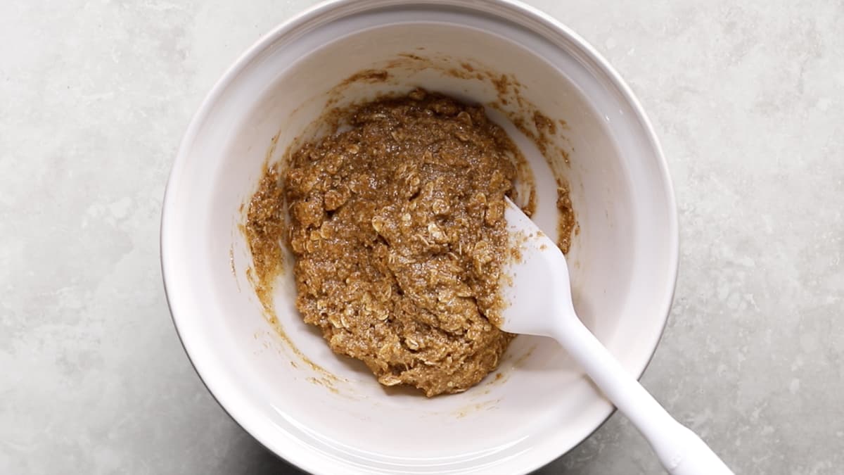 Oatmeal cookie dough in a mixing bowl with a spatula before raisins are added