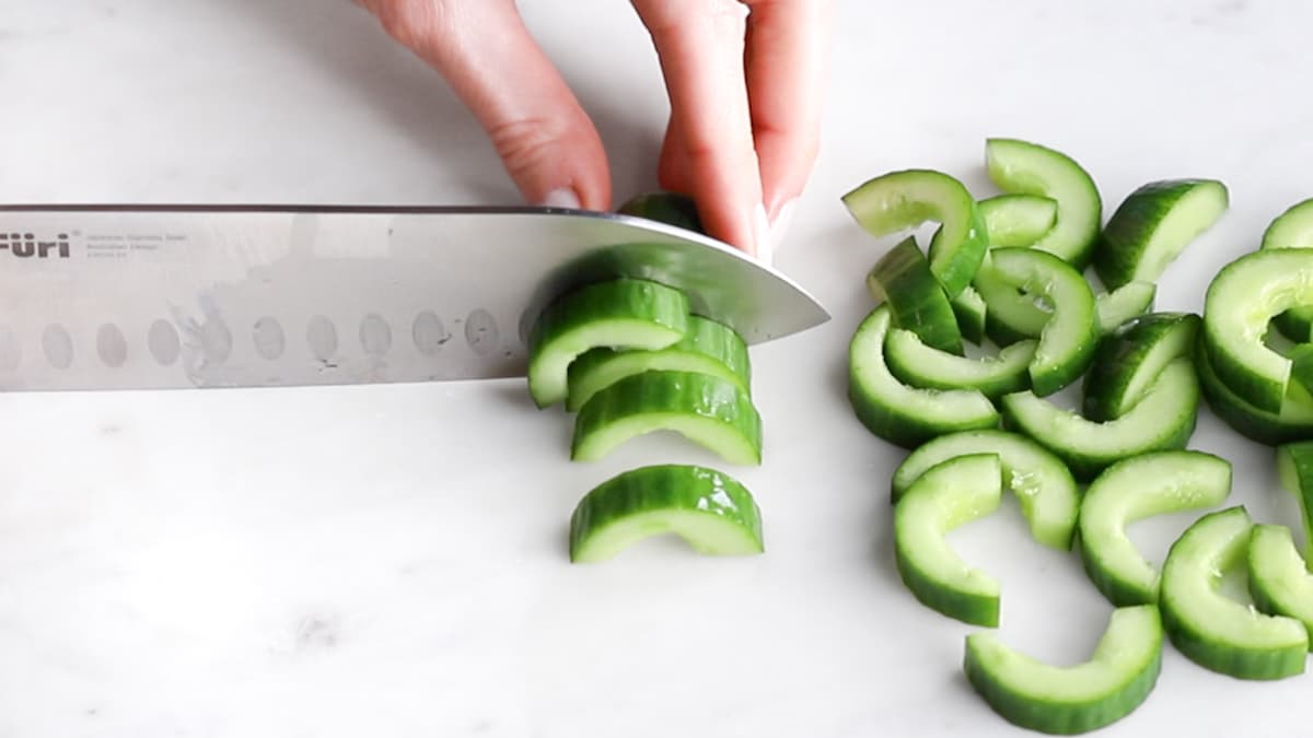 Deseeded cucumber being sliced with a large knife