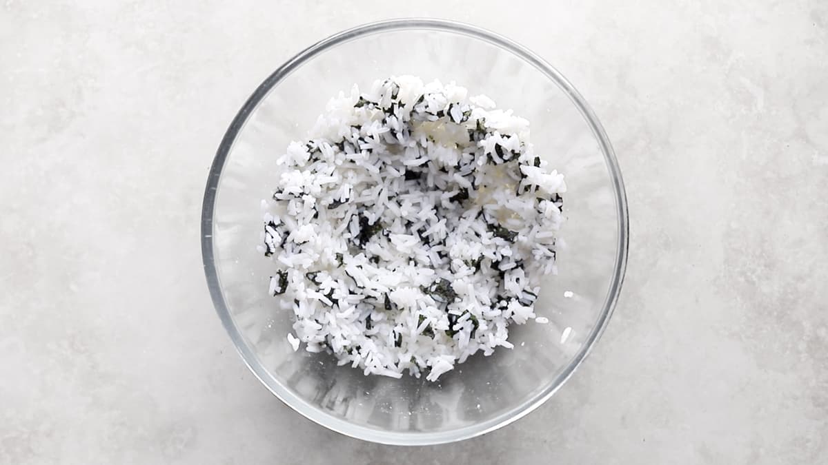 Cooked white rice mixed with small pieces of nori in a bowl