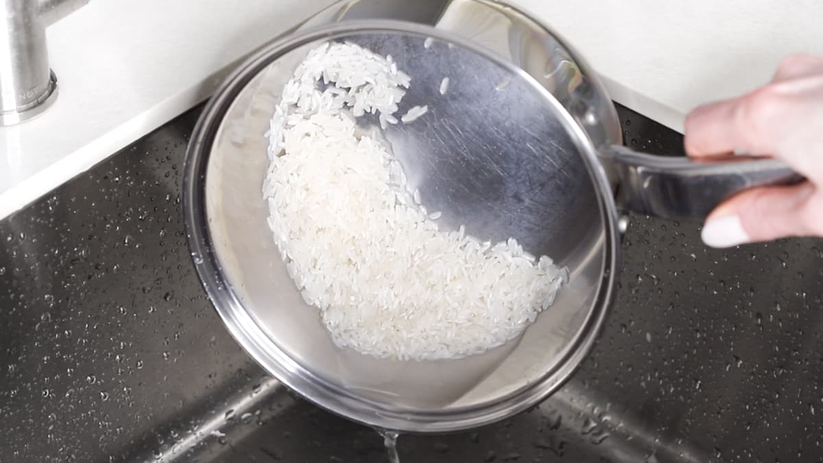 White rice in a saucepan with water being drained